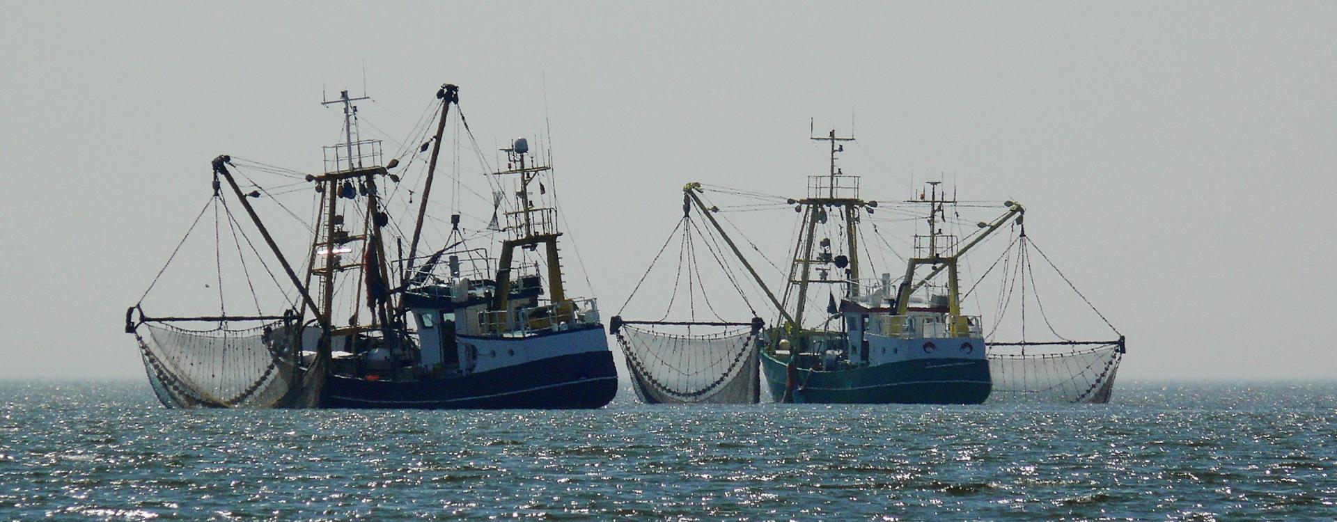 Two fishing boats with nets hanging